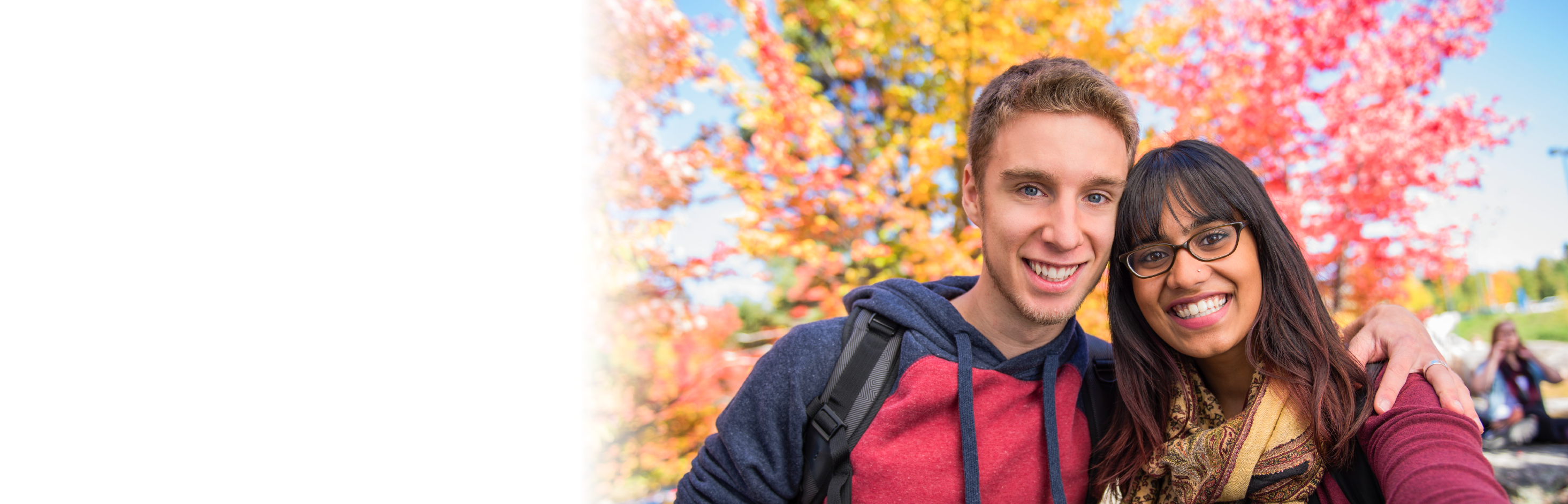 Image of two students in front of a colourful, treed background