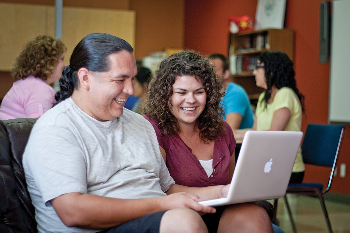 Two people sit together working on a computer.