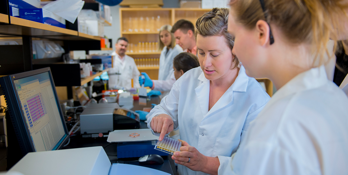 students and instructors examine lab samples