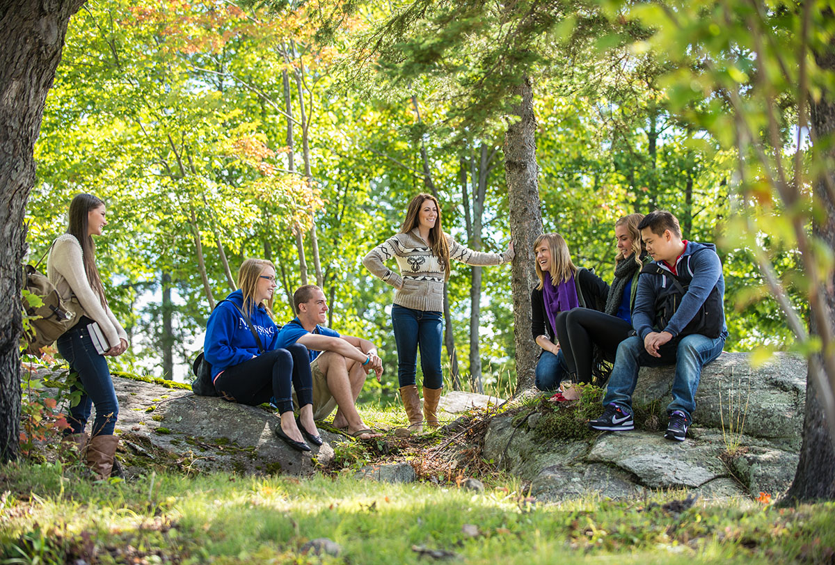 Group of students sit outside in nature.