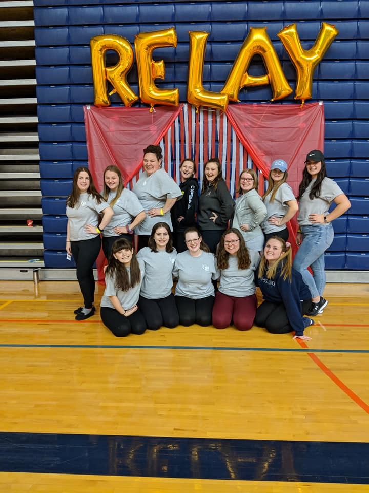 Picture of 13 students in front of a Relay balloon