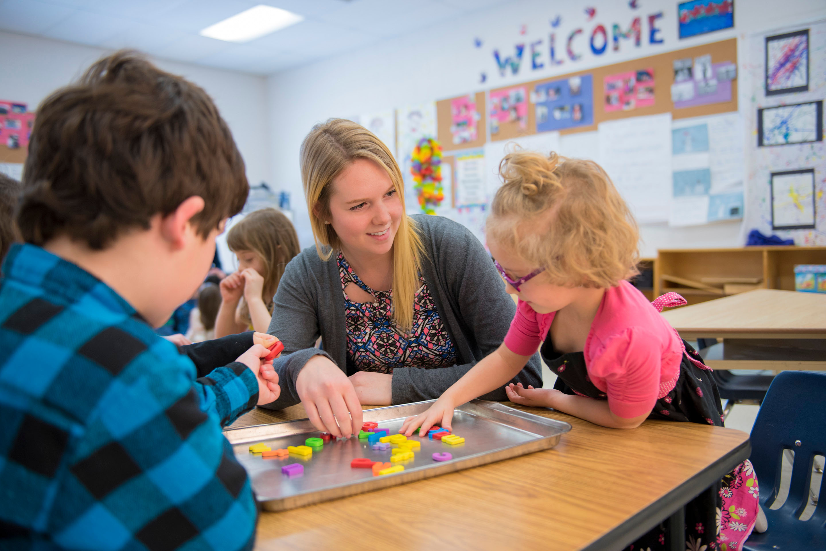 A teacher playing games with a child in pink