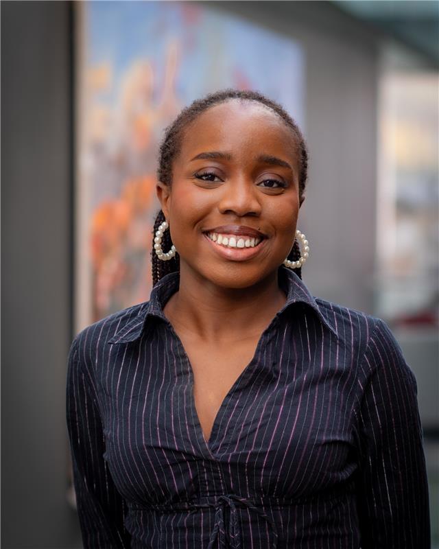 A woman in navy striped shirt in front of a blurred background