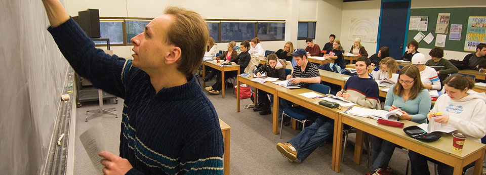 professor writing on chalkboard