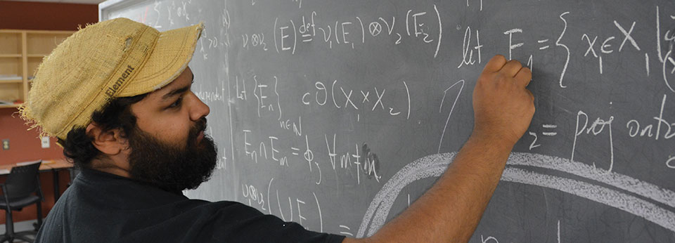 student writing on chalkboard