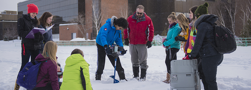 students drilling through the ice on the pond