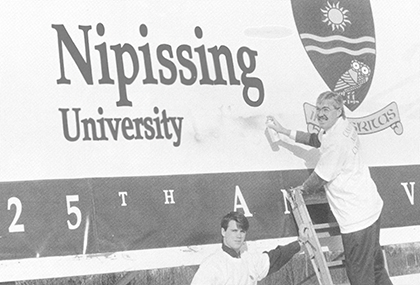 Dave Marshall with the Nipissing University 25th anniversary banner