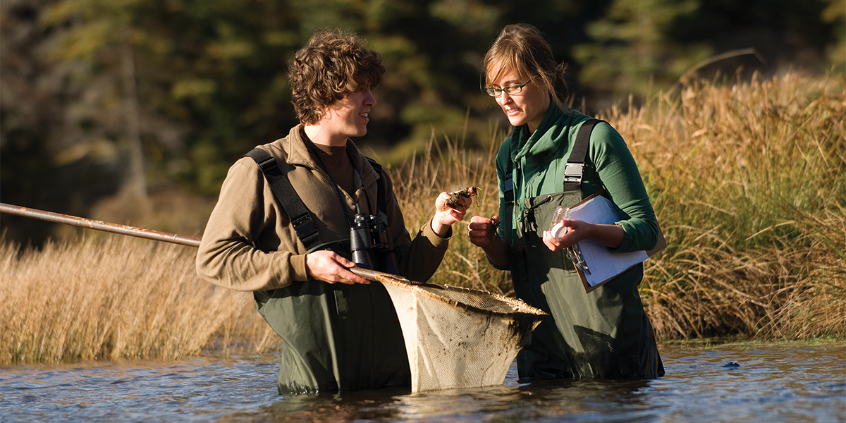 student in hip-waders study pond life