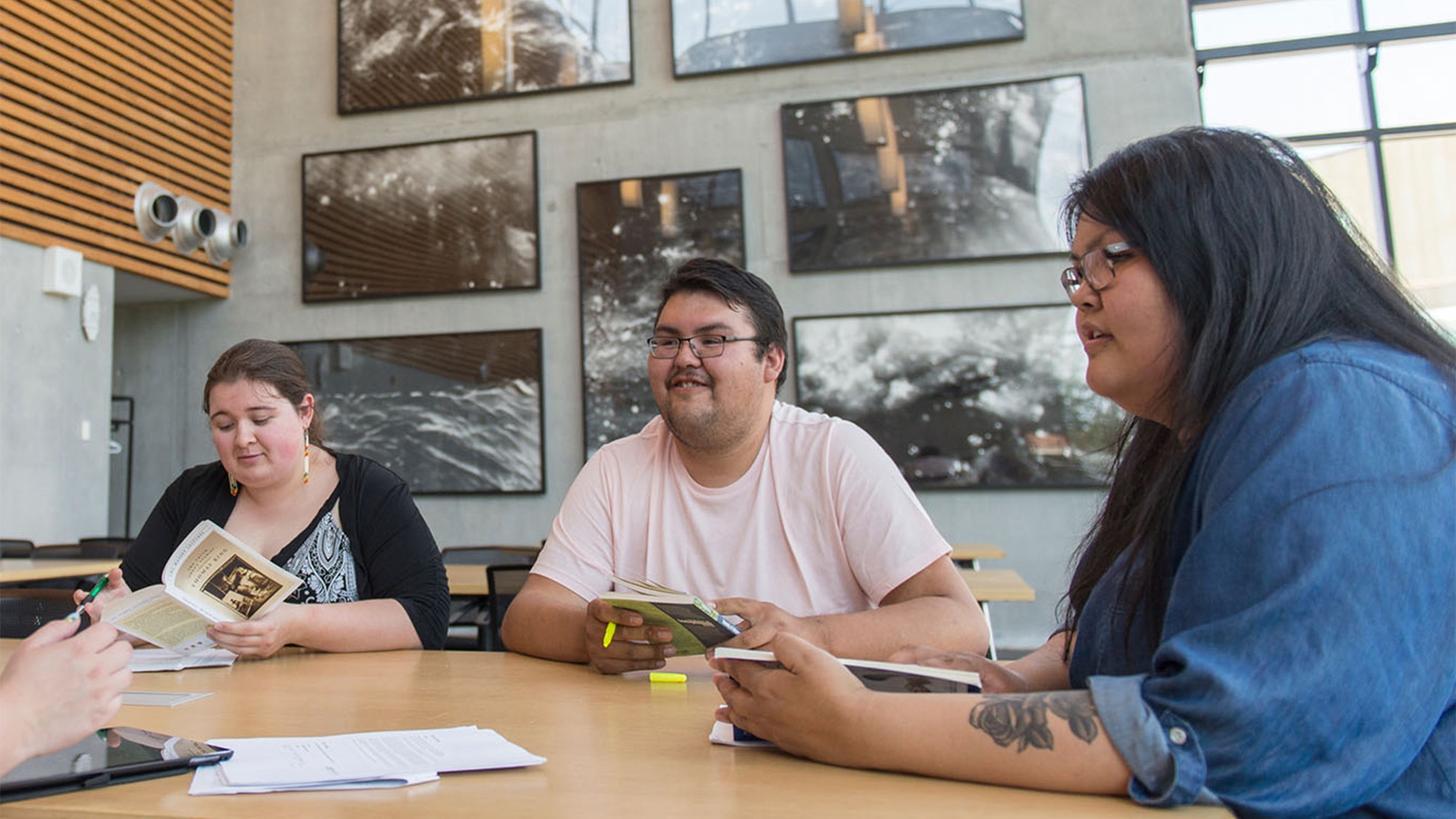 3 students reading books in the library 