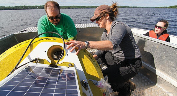 Watershed Hydrology Lab field research - 3 people on a boat in the middle of a lake taking measurements