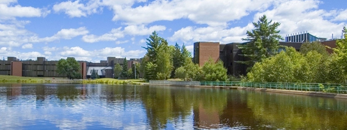 Blue cloudy sky reflecting on the pond at Nipissing University