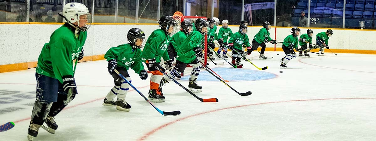 youth in green jerseys line up on ice