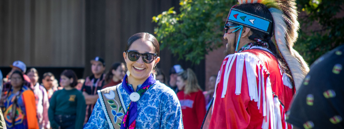 Photo of two pow wow participants donning Indigenous regalia.