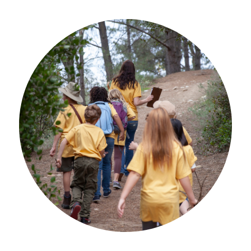 Children at camp hiking through trails as a group.