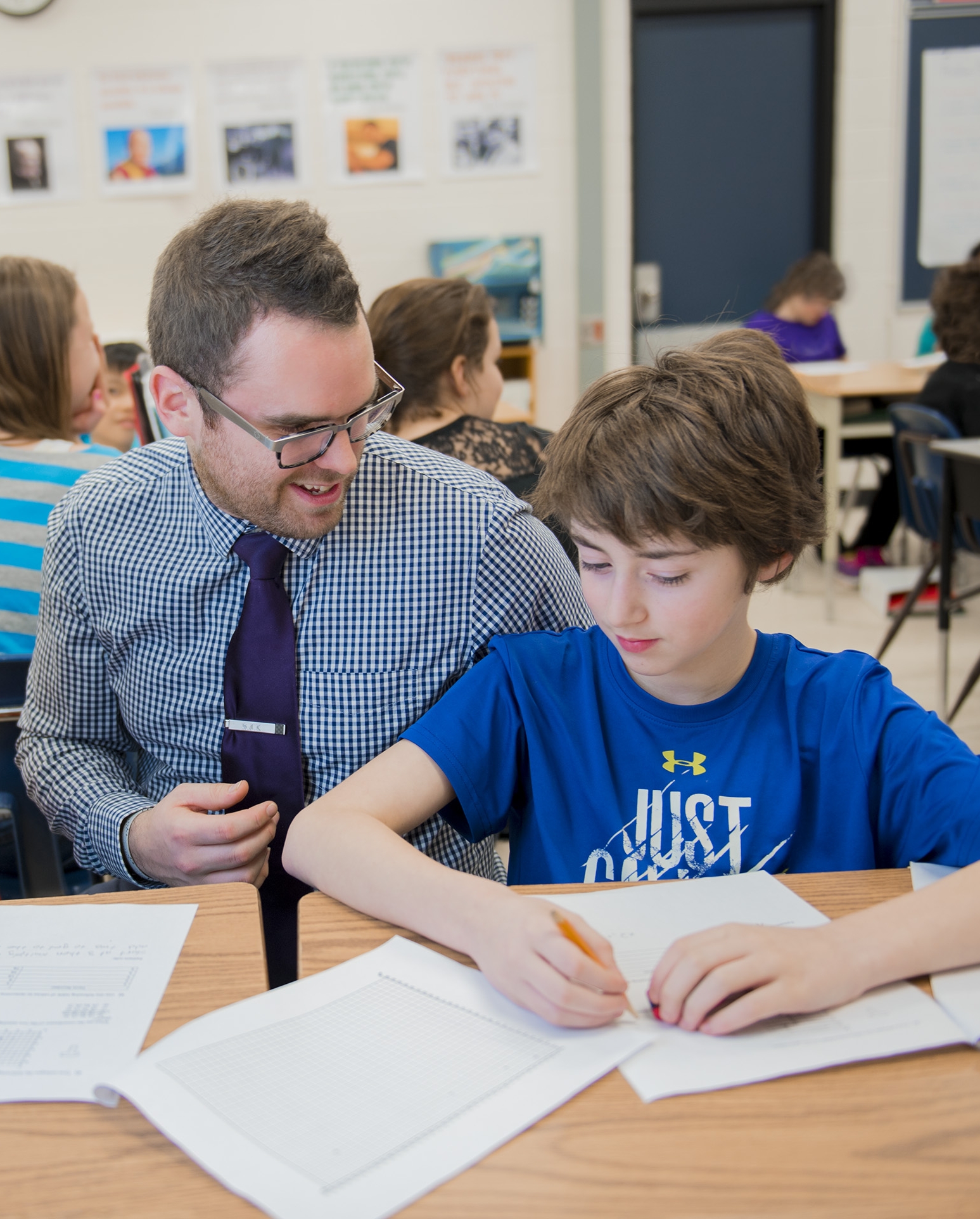 A teacher helping 2 students at a desk