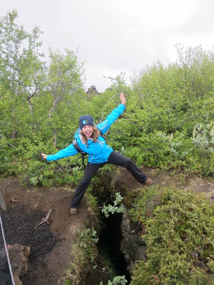 Photo of woman excitedly straddling outdoor crevice