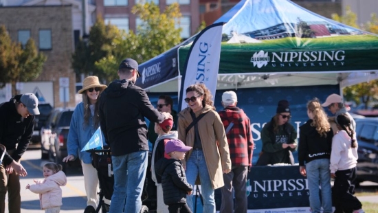 Families socializing in front of Nipissing University pop up shop during NU Homecoming 2025