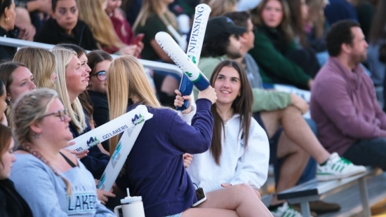 Two Lakers playing with thunder sticks during NU Homecoming 2025