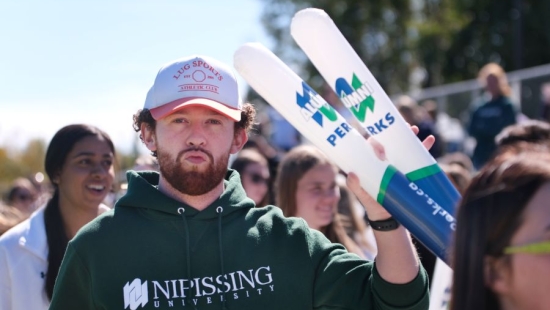 Laker is holding thunder sticks during NU Homecoming 2025