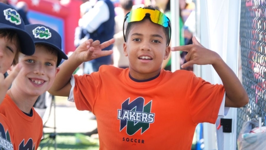 Young boys posing in orange shirts that read "NU Lakers Soccer" during NU Homecoming 2025