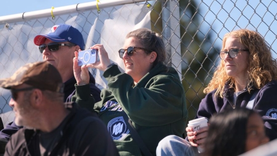Woman is taking a picture of NU Homecoming 2025 games, others watching
