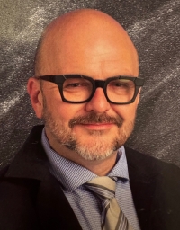 Shawn Darby from the shoulder up in front of a grey textured background