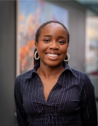 A woman in navy striped shirt in front of a blurred background