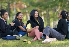 A group of international students sitting in a forested area on Nipissing University Campus.