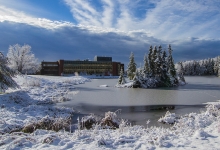 Winter scene of campus including snowcovered trees and frozen pond