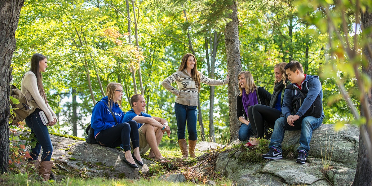 Group of students sit outside in nature.