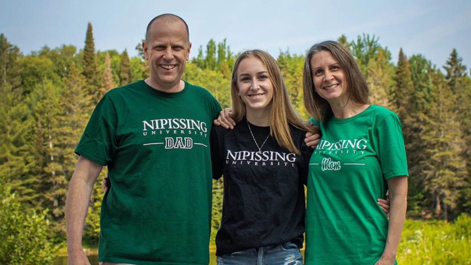 parents and a student posing in front of the pond