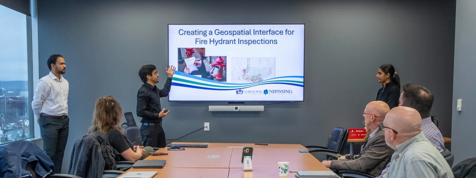 Keshav Singh, Lovepreet Kaur, and Sagar Tewatia presenting their GIS projects in the CIty Hall Executive Boardroom