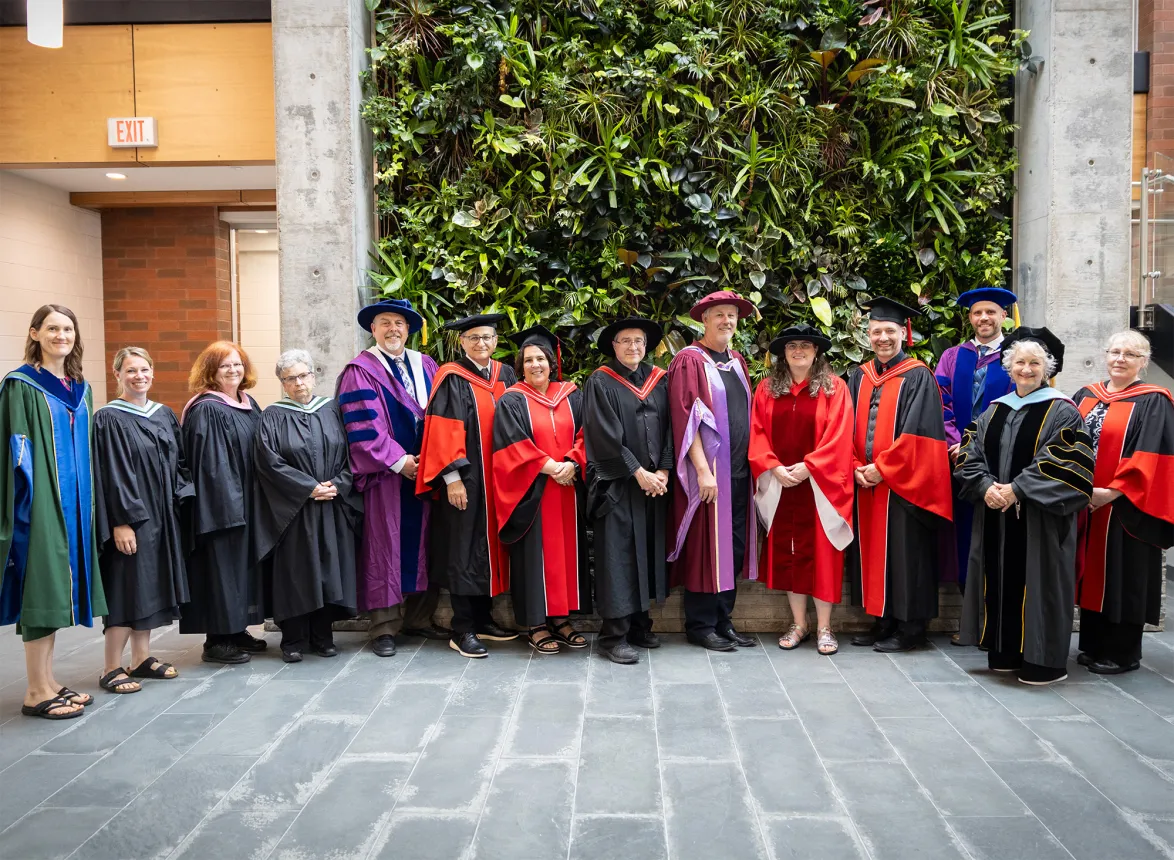 A group of faculty in front of the living wall in the athletic centre