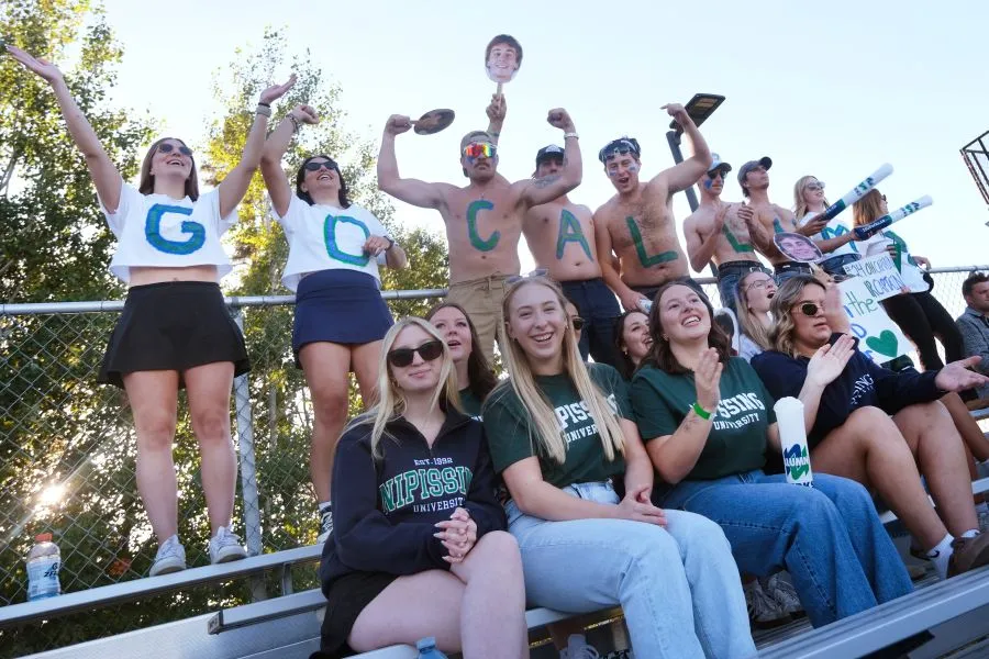 Lakers cheering during games, people in the back row have letters "GO CALLUM" written on them