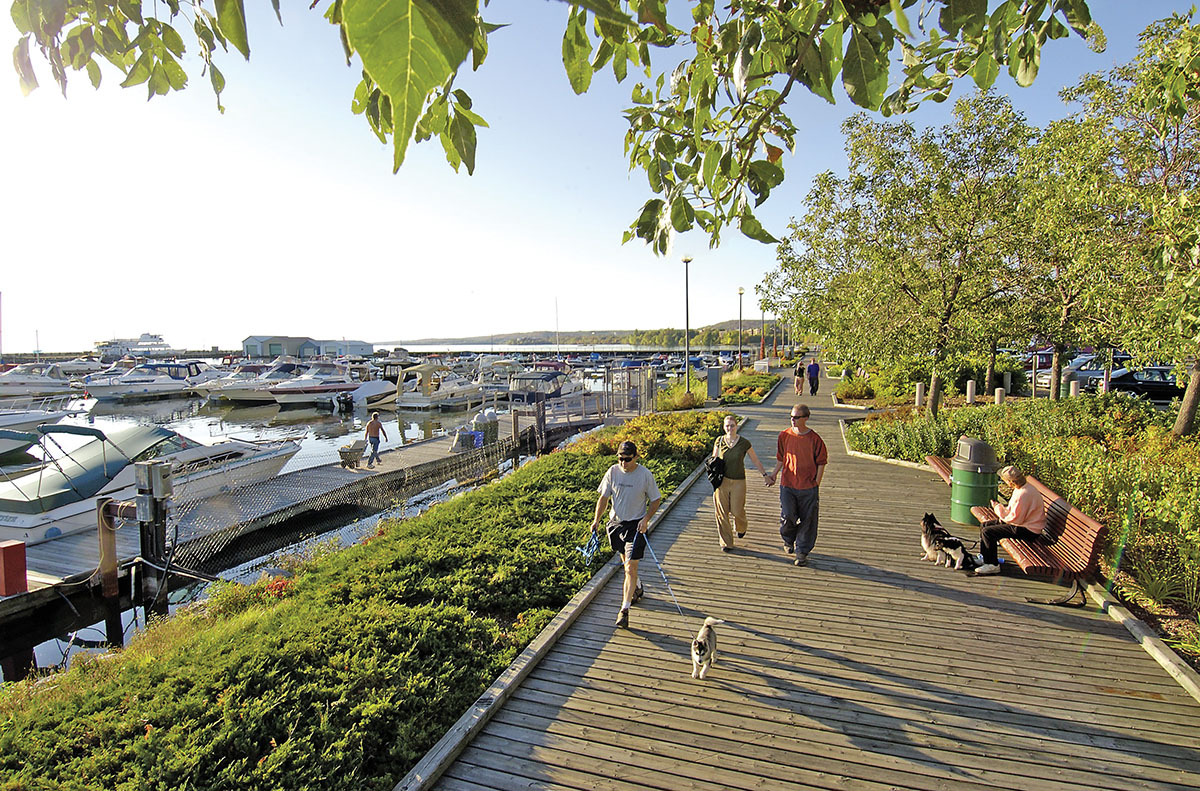 People walk the North Bay Waterfront Boardwalk at sunset.